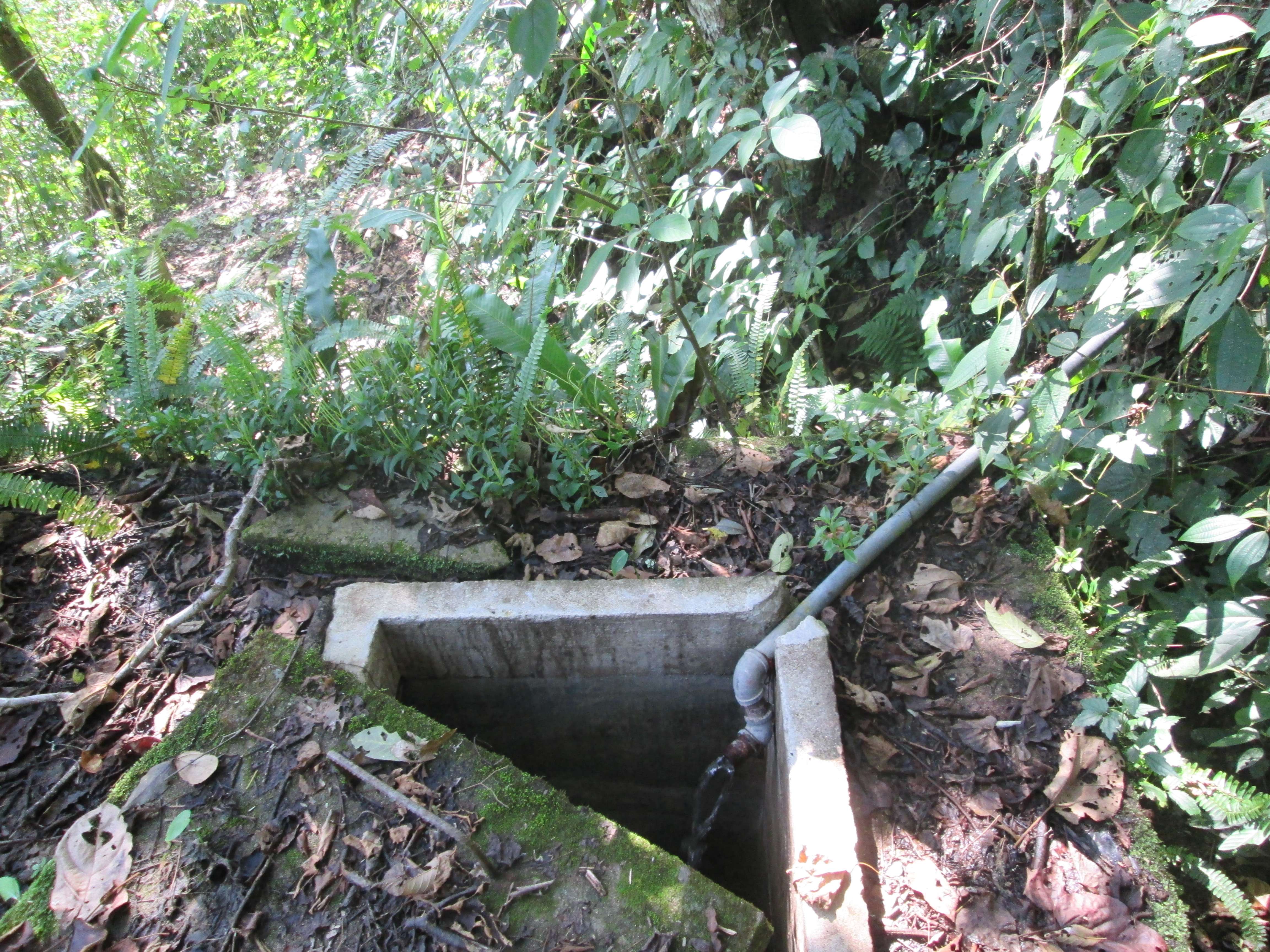 A concrete block, with a concrete door pulled away to reveal a flowing water spout