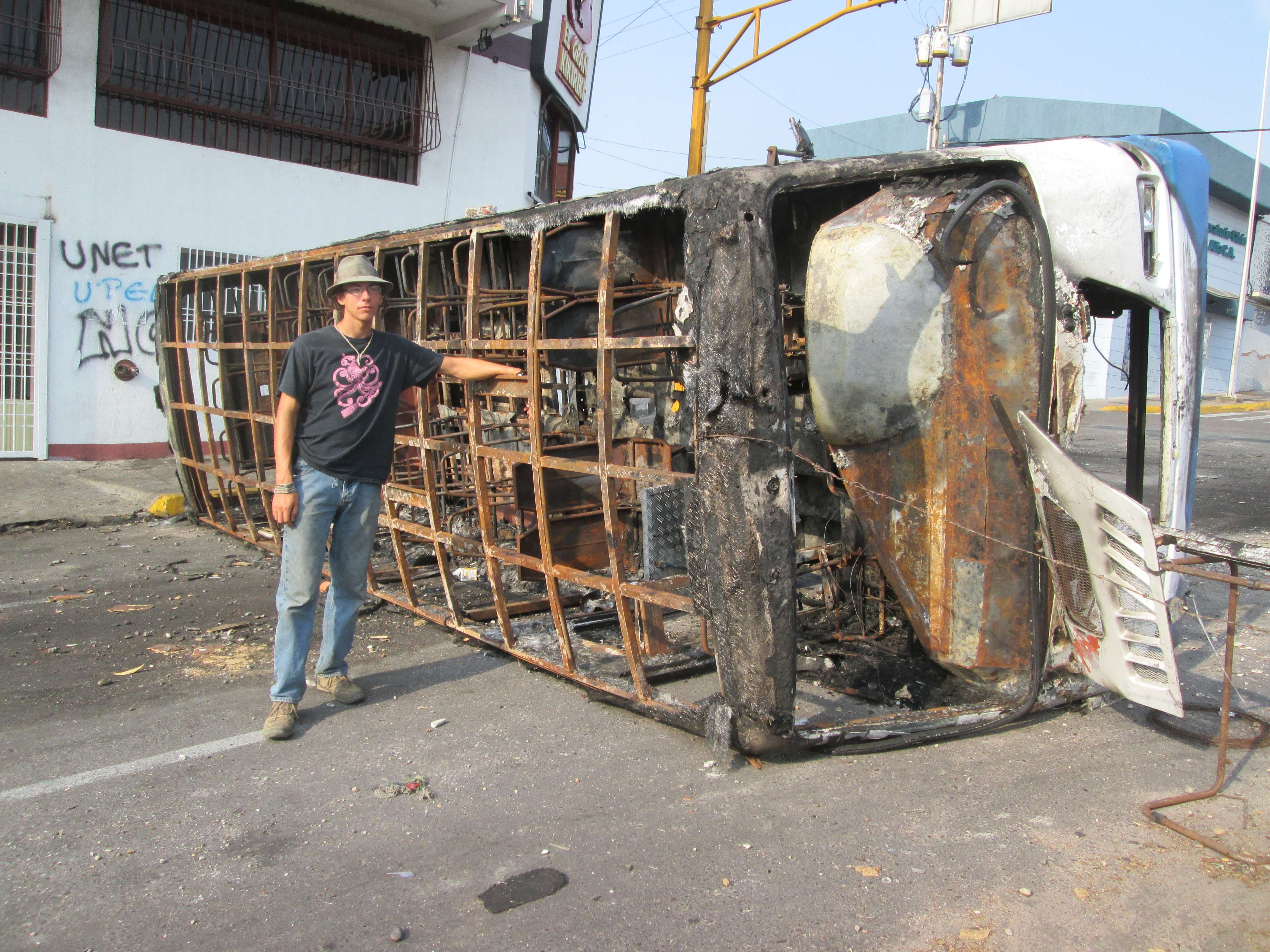 Leaning against a bus that was destroyed in a riot